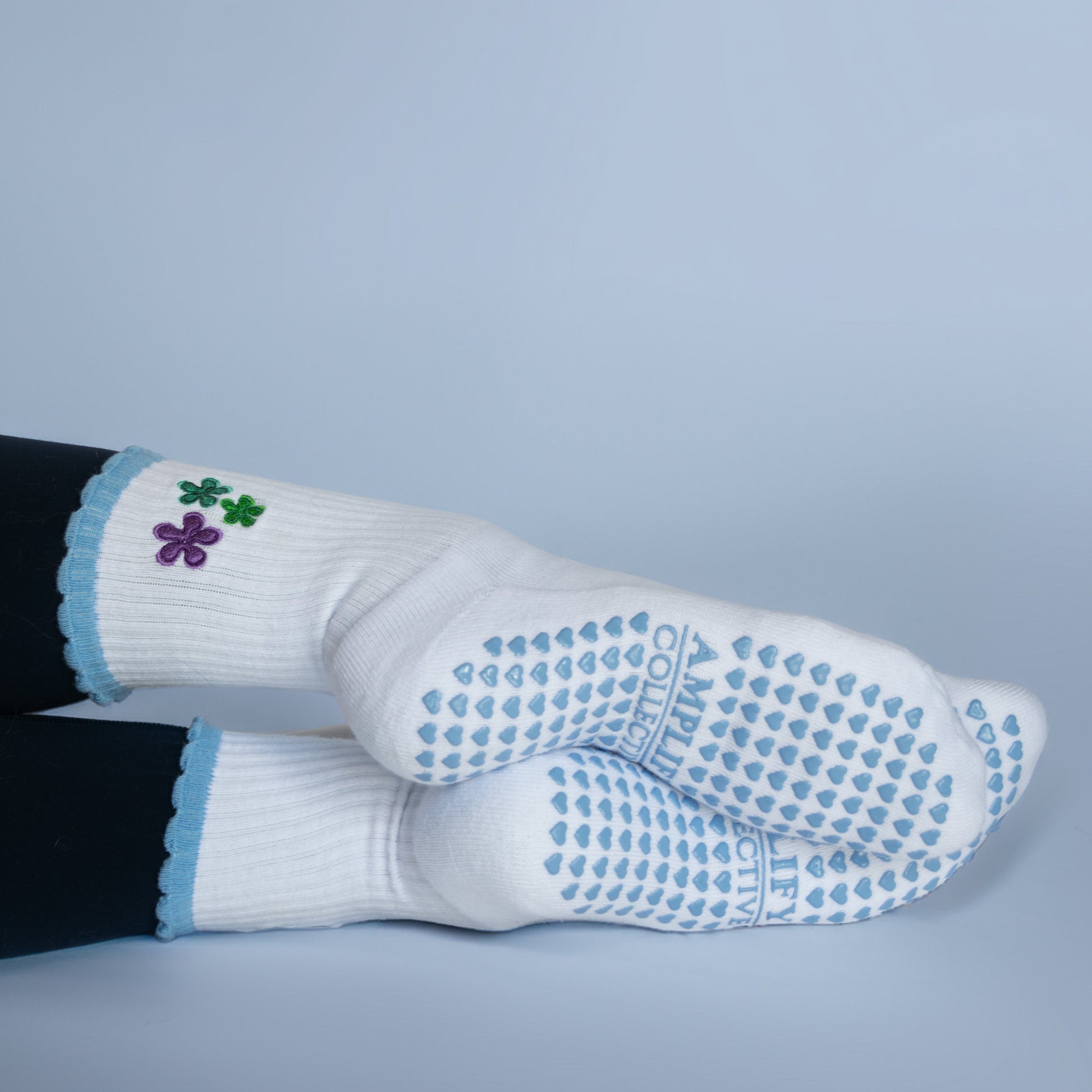 White socks with blue textured sole and floral design on a light gray background