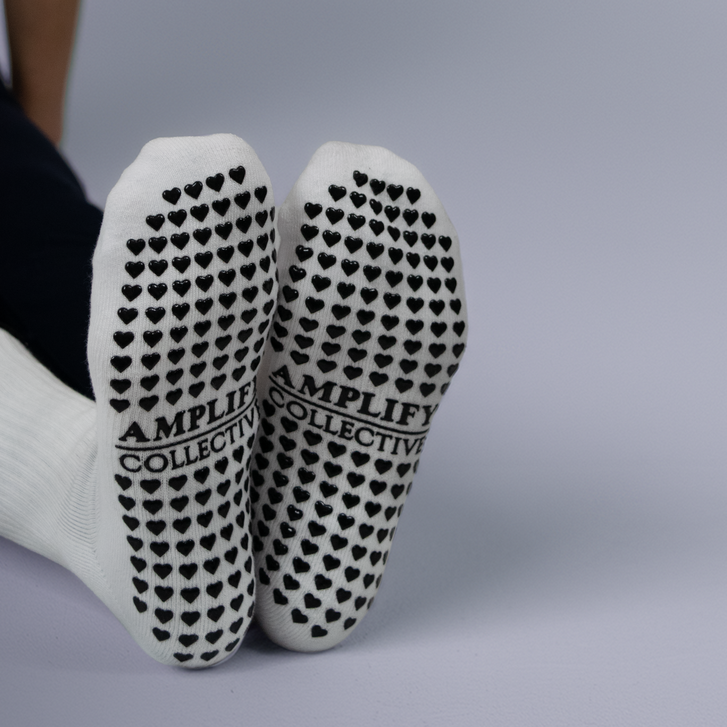 AMPLIFY COLLECTIVE black text on the bottom of a white pilates sock.