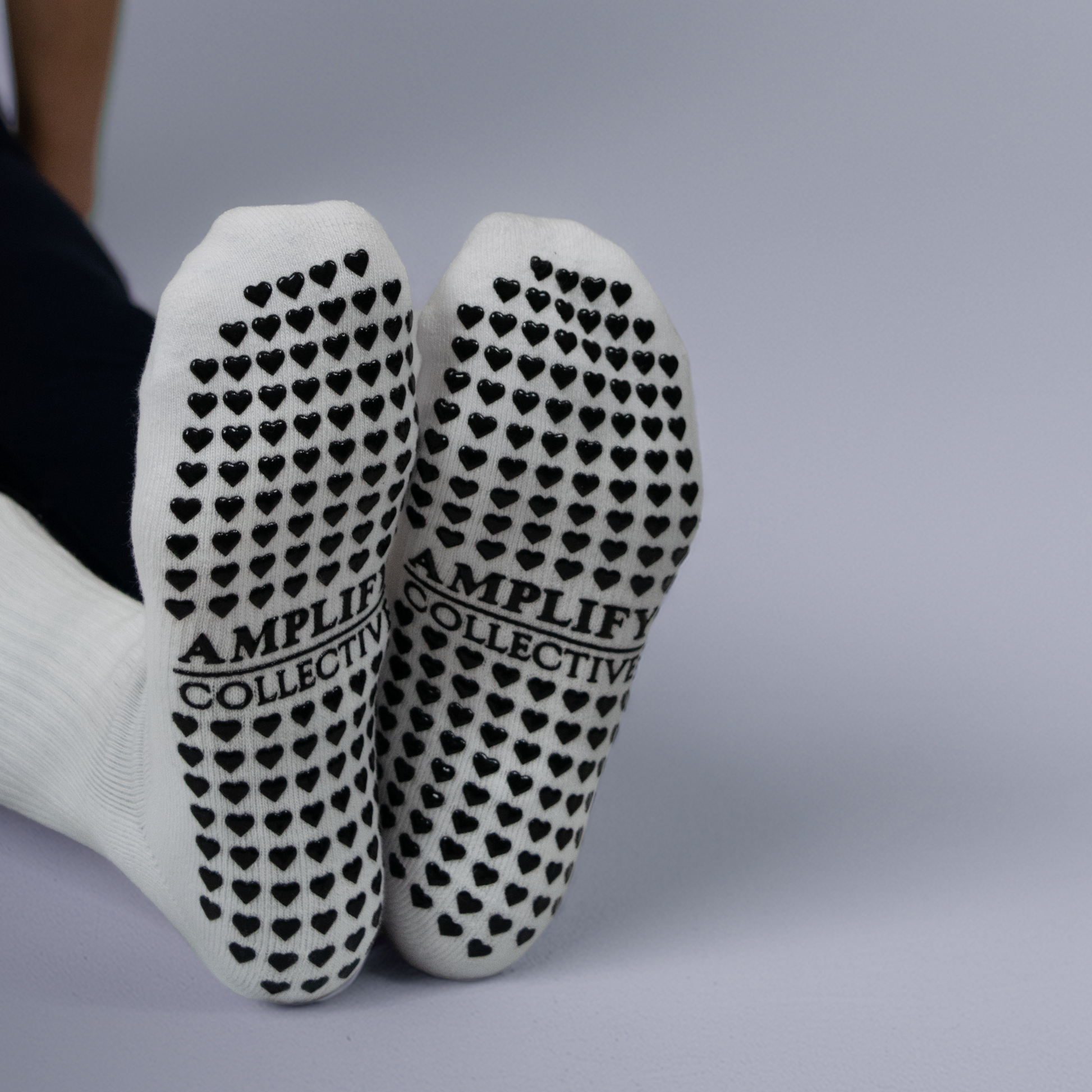 AMPLIFY COLLECTIVE black text on the bottom of a white pilates sock.